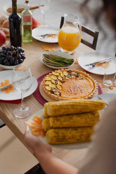 Cropped view of tasty thanksgiving dinner near blurred african american woman with corn  - Фото, зображення