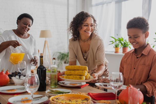 Smiling african american woman looking at son near mother and thanksgiving dinner  - Foto, Imagen