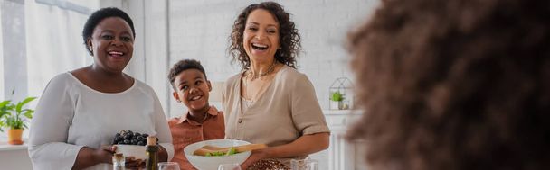 感謝祭の間にぼやけた女の子を見て食べ物を持つ陽気なアフリカ系アメリカ人の家族、バナー  - 写真・画像