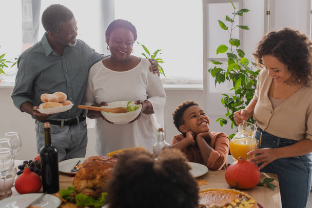 Smiling african american family serving thanksgiving dinner near kids  - Fotó, kép