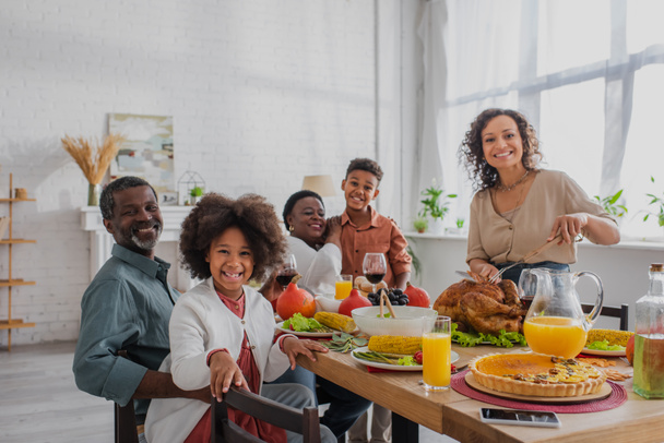 Smiling african american family celebrating thanksgiving with turkey at home  - Foto, imagen