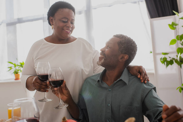Smiling african american couple toasting wine during thanksgiving dinner  - Φωτογραφία, εικόνα
