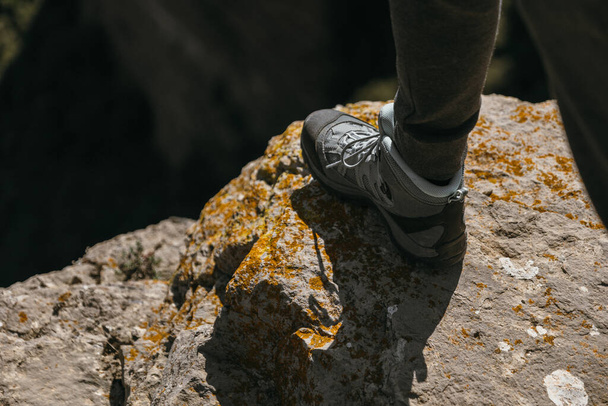 Szczegóły buta trekkingowego podczas wędrówki w górach, stąpając po krawędzi klifu. - Zdjęcie, obraz