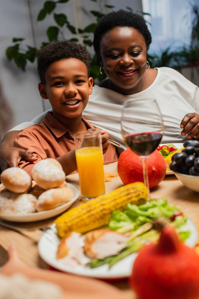 Веселый африканский американец улыбается рядом с счастливой бабушкой во время праздничного ужина - Фото, изображение