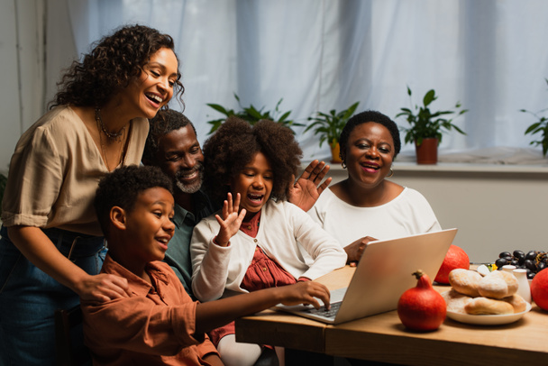 happy african american family waving hands during video call during thanksgiving dinner - Valokuva, kuva