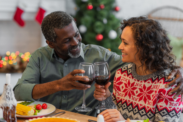 gioioso afro-americano padre e figlia clicking bicchieri di vino rosso durante la cena di Natale - Foto, immagini