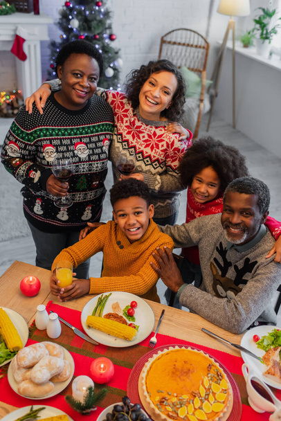 high angle view of joyful african american family looking at camera during christmas dinner - Photo, Image