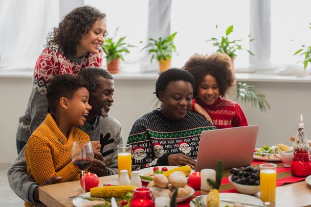 クリスマスディナーのビデオ通話中にアフリカ系アメリカ人の家族が笑顔で - 写真・画像