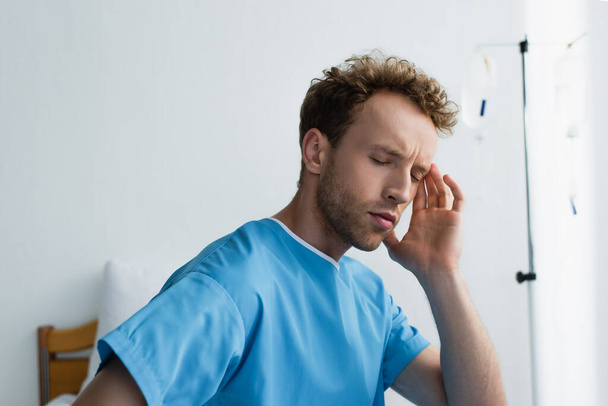 Patient mit geschlossenen Augen mit Kopfschmerzen im Krankenhaus  - Foto, Bild