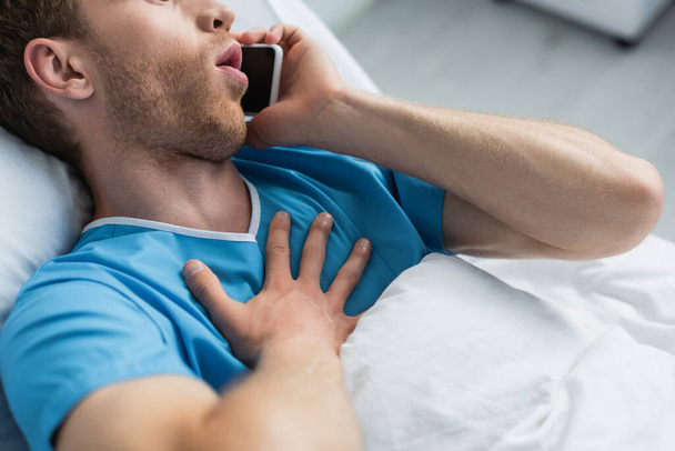 vágott kilátás férfi beszél okostelefon kórházi ágyban - Fotó, kép
