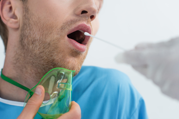 vista recortada del médico sosteniendo hisopo cerca del paciente con la boca abierta mientras hace la prueba de pcr - Foto, Imagen