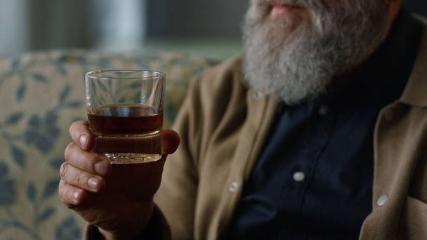 Elderly man holding glass whiskey in hands. Rest enjoy retirement life concept - Photo, Image