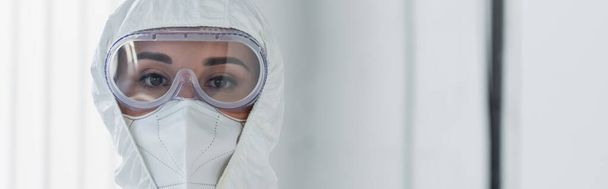 врач в индивидуальной защитной экипировке и очках, смотрящий на камеру, баннер - Фото, изображение