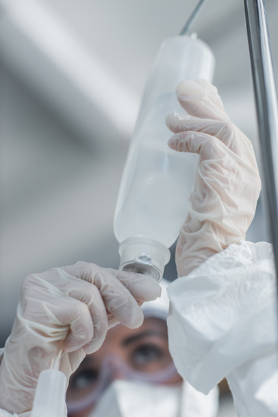 cropped view of doctor in latex gloves holding catheter on drop counter - Photo, Image