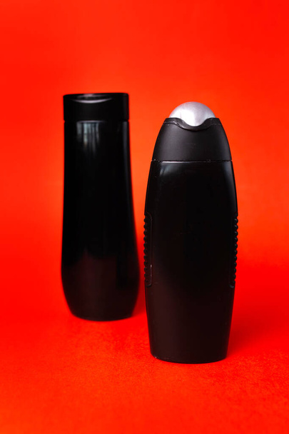 Két fekete műanyag palack piros alapon. - Fotó, kép