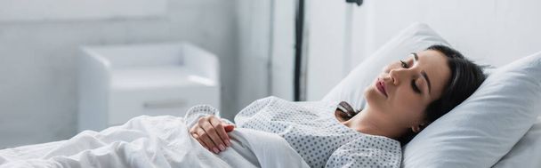 brunette woman in patient gown lying in hospital bed, banner - Fotoğraf, Görsel