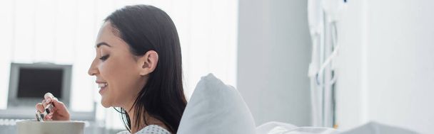 vista lateral da mulher alegre segurando tigela com café da manhã no hospital, banner - Foto, Imagem