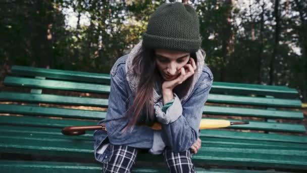 Nastolatka ziewa siedząc na ławce w parku - Materiał filmowy, wideo