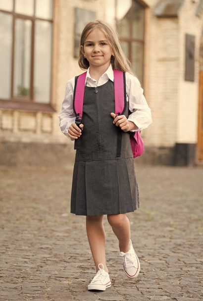 Felice bambino piccolo in uniforme formale portare la borsa della scuola all'aperto, 1 settembre - Foto, immagini