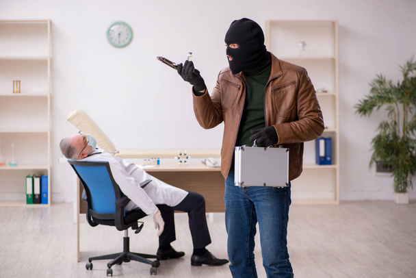 Человек в маске грабитель крадет вакцину у старого доктора - Фото, изображение