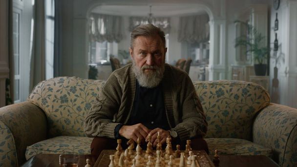 Pozorný starší muž si myslí, že šachová partie je doma. Starší hráč hraje šachy - Fotografie, Obrázek