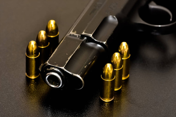foto de una pistola negra y balas sobre un fondo negro - Foto, Imagen