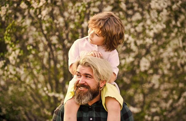 Happy family. Fathers day. Child having fun with dad. Little boy and father in nature background. Springtime. Hipster piggybacking baby. Bearded brutal man good father. Dad and son. Best dad ever - Photo, image
