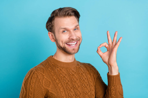 Photo of positive charming young man make okay sign good mood recommend isolated on blue color background - Zdjęcie, obraz
