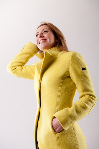 real woman in yellow coat smiling - Photo, Image