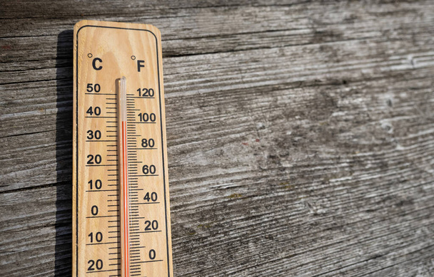 Wooden thermometer with red measuring liquid showing high temperature over 32 degrees Celsius on sunny day on old wooden background. Concept of heat wave, warm weather, global warming, climate change - Fotoğraf, Görsel