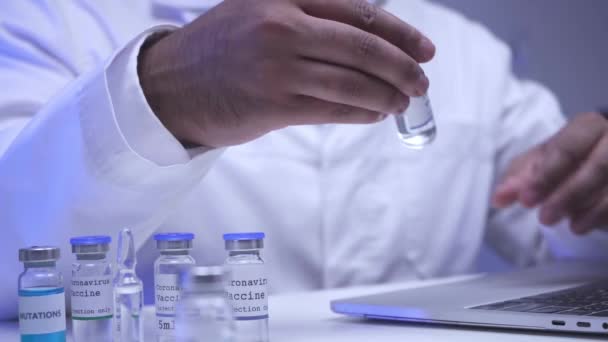 Обрезанный вид ученого, использующего ноутбук и принимающего вакцину в лаборатории  - Кадры, видео