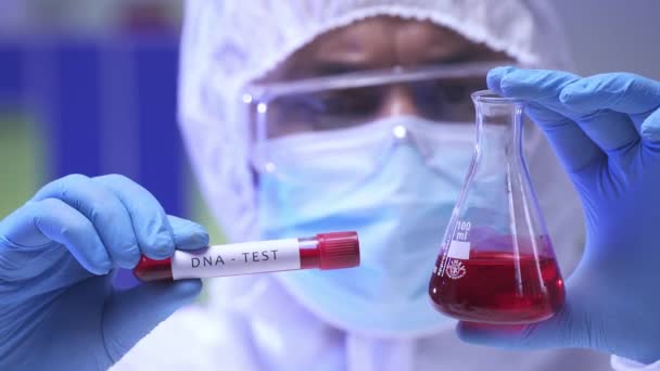 Científico indio borroso sosteniendo matraz y tubo de ensayo con prueba de ADN en laboratorio - Metraje, vídeo