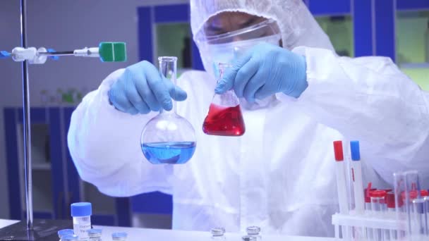 Científico indio agitando muestras en frascos y tomando portapapeles en laboratorio  - Metraje, vídeo