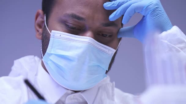 Indischer Wissenschaftler in medizinischer Maskenschrift mit Stift isoliert auf lila  - Filmmaterial, Video