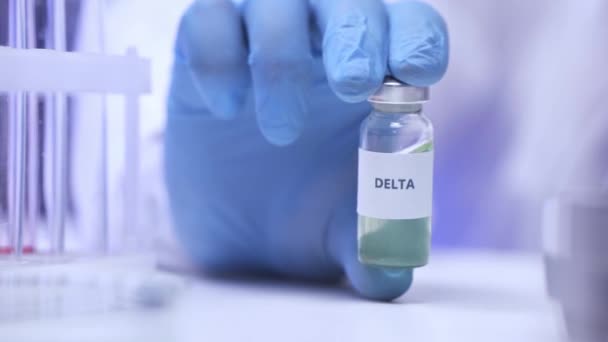 Oříznutý pohled vědce v latexové rukavici držící sklenici s písmem delta  - Záběry, video