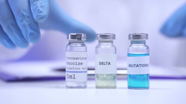 Widok naukowca piszącego na schowku w pobliżu szczepionek przeciw koronawirusowi  - Materiał filmowy, wideo