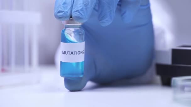 Vue recadrée du scientifique en gant de latex secouant pot avec des mutations lettrage - Séquence, vidéo