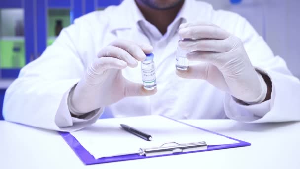 Oříznutý pohled vědce držícího sklenice s vakcínami v blízkosti schránky v laboratoři  - Záběry, video