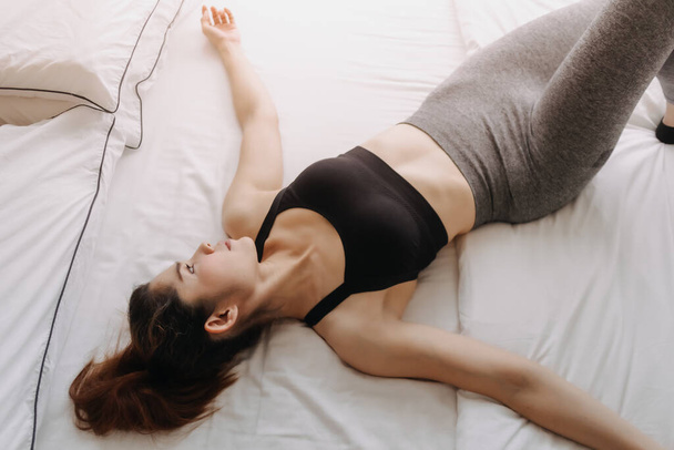 スポーツの女性はトレーニング後にベッドの上で休息を身に着けている. - 写真・画像