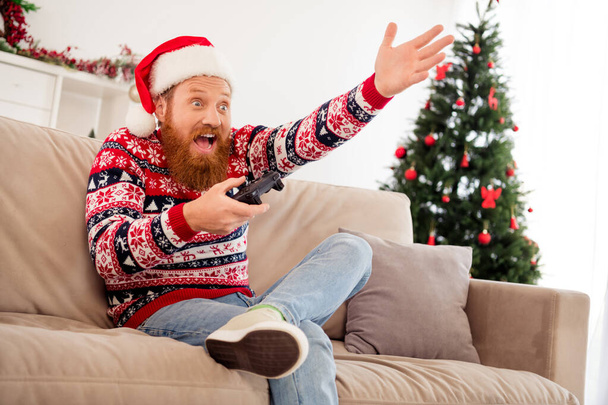 Photo of happy funky screaming male playing playstation win game scream shout wear santa claus sit sofa couch at home - Фото, зображення