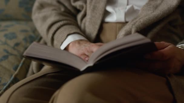 Closeup volwassen vrouw handen flippen boekpagina 's binnen. Oudere vrouw leest - Video