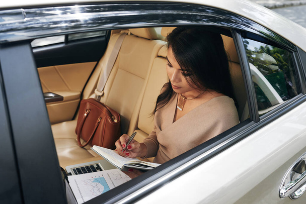 Азиатская предпринимательница готовит отчет в автомобиле - Фото, изображение