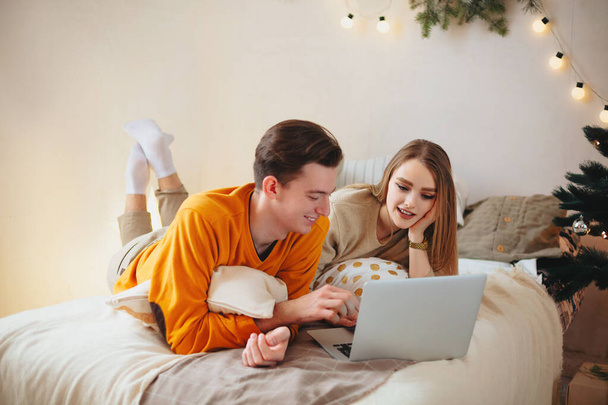 Portrait of smiling happy couple with laptop on sofa at home - Photo, Image