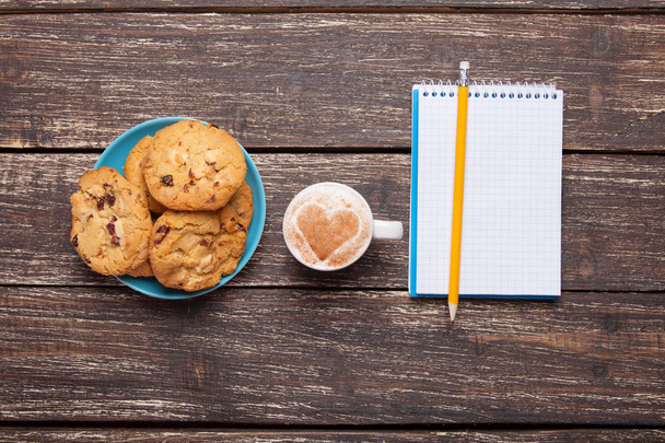 Cookie i filiżanka z kawą, ołówkiem i notatnikiem. - Zdjęcie, obraz