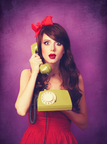Beautiful brunette girl with telephone on violet background. - Foto, Bild