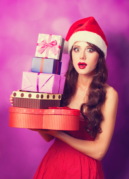 schöne brünette Mädchen in Weihnachtsmütze mit Geschenken auf violett b - Foto, Bild