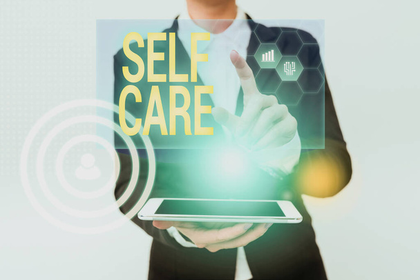 Inspiration showing sign Self Care. Business showcase practice of taking action preserve or improve ones own health Woman In Uniform Holding Mobile Phone Showing Futuristic Virtual Icons - Photo, Image