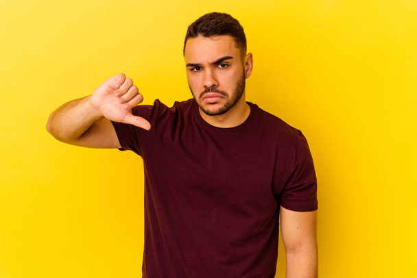Young caucasian man isolated on yellow background showing a dislike gesture, thumbs down. Disagreement concept. - Photo, Image