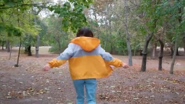 Jonge vrouw met donker haar met armen reikend in het park, positieve energie geluk in vrijheid levensstijl, ontsnappen weg te komen, menselijke kracht en vrijheid van de natuur levensstijl - Video