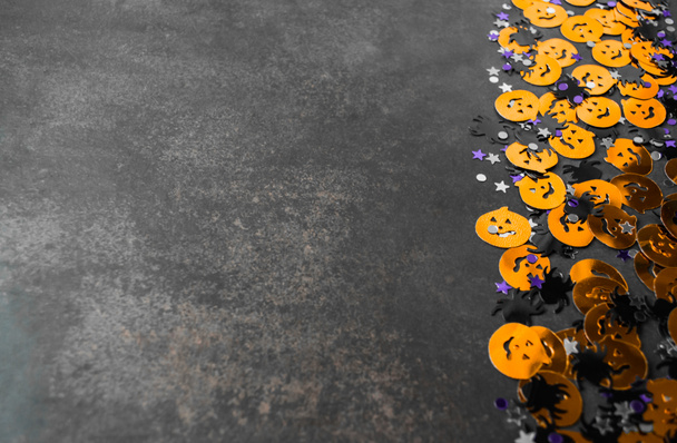 Hintergrund zu Halloween: Konfetti in Form orangefarbener Kürbisse, schwarzer Spinnen und Sterne. Grauer Hintergrund. Kopierraum. - Foto, Bild